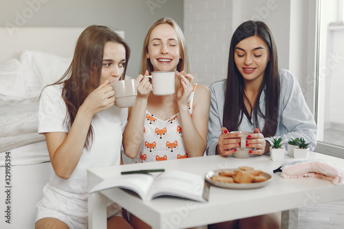 Girls in a pajamas. Friends have fun at home. Ladies drinking a coffee.