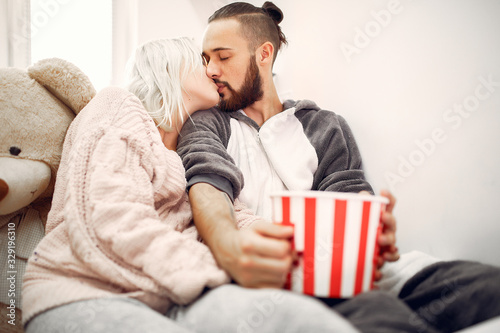 Cute couple in a bedroom. Lady in a pink sweater. Pair at home with a popcorn