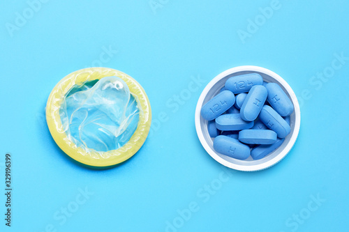 Condom with PrEP ( Pre-Exposure Prophylaxis) used to prevent HIV, in plastic pill bottle cap on blue background. Save sex photo
