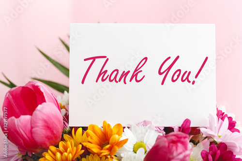 Thank you card in beautiful flowers bouquet on pink background. White blank card with space for text, frame mockup for invitation. Spring festive flowers