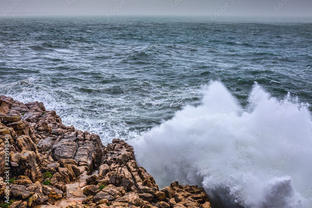 Fototapeta premium A huge ocean waves breaking on the coastal cliffs in at the cloudy stormy day. Breathtaking romantic seascape of ocean coastline.