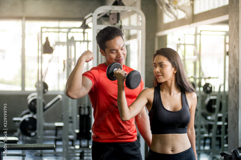 The interesting male trainer teaches how to give dumbbells to attractive women and smiley faces in the gym. The interesting male trainer teaches how to give dumbbells to attractive women and smiley faces in the gym.