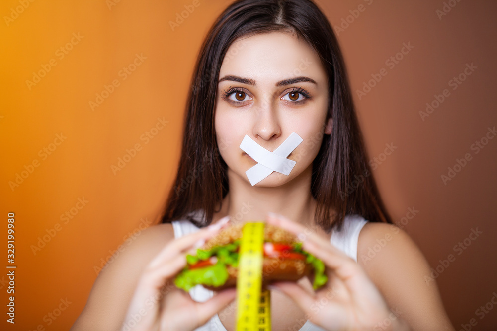 Portrait woman wants to eat a Burger but stuck skochem mouth, the concept of diet Portrait woman wants to eat a Burger but stuck skochem mouth, the concept of diet