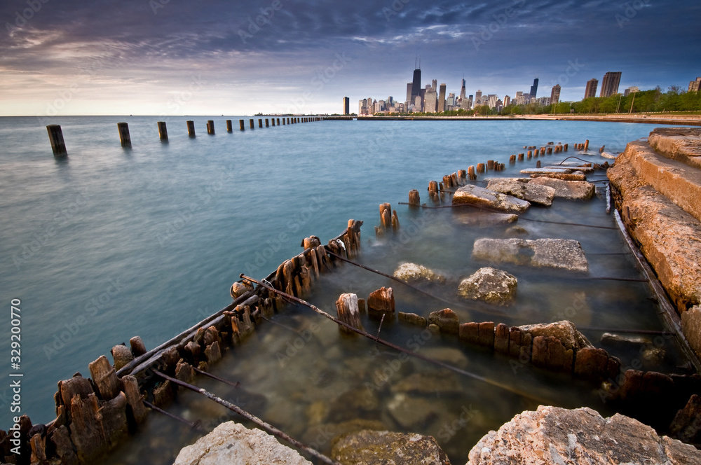 A deteriorating seawall on the Chicago lakefront with the city skyline in the background.