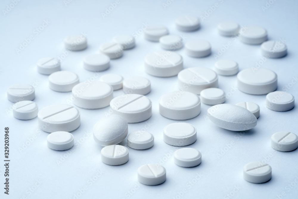 Closeup of white tablets on a white background with texture. Closeup of white tablets on a white background with texture.
