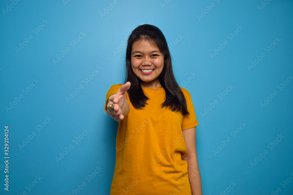 Portrait of Young beautiful asian women with blue isolated background, smile look at the camera and offering handshake gesture Portrait of Young beautiful asian women with blue isolated background, smile look at the camera and offering handshake gesture