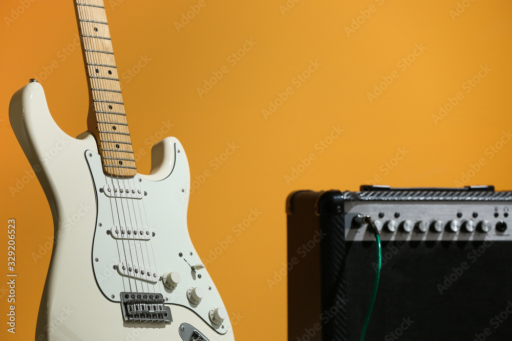 Naklejka premium Modern guitar and amplifier on color background