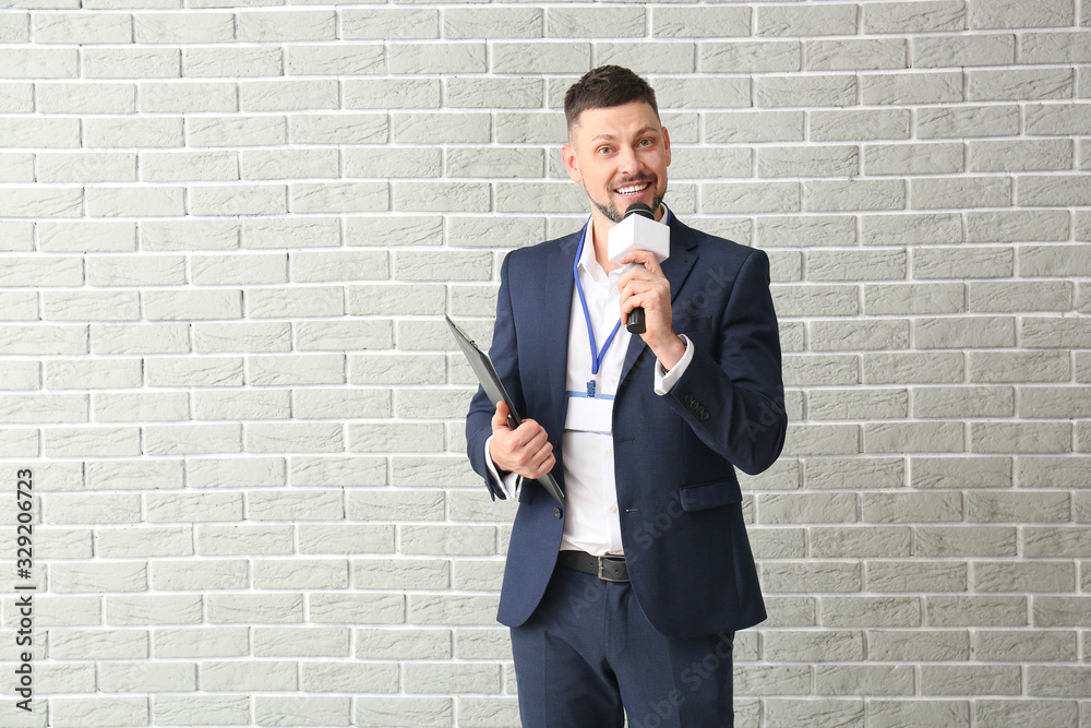 Male journalist with microphone on brick background Male journalist with microphone on brick background