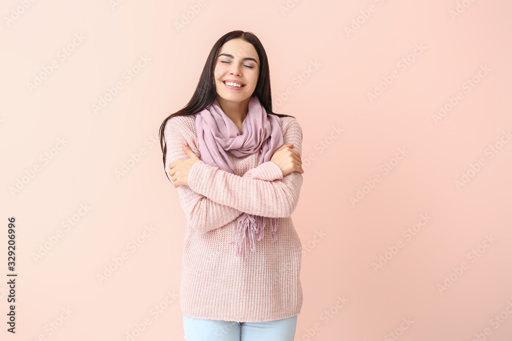 Obraz premium Beautiful young woman in warm sweater on color background