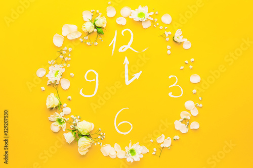 Creative clock made with flowers on color background