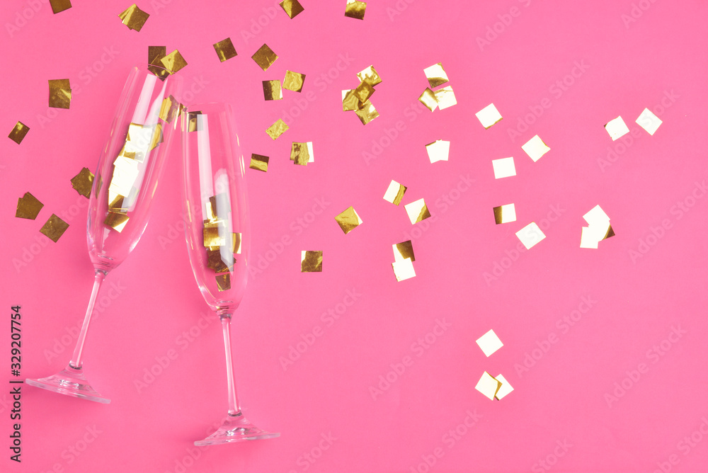 Glasses for champagne with confetti on color background