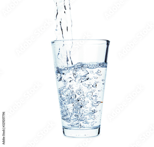 Pouring of fresh water in glass on white background