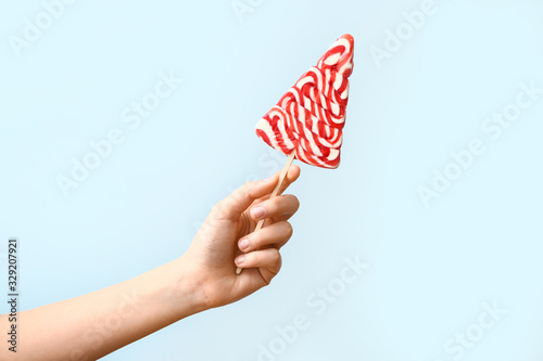 Female hand with sweet lollipop on light background © Pixel-Shot