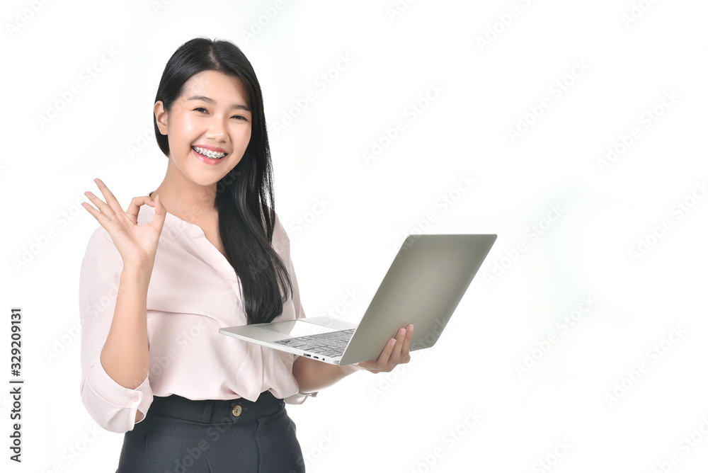 Beautiful Asian woman wearing braces are holding a laptop and pose OK in white isolated background. Finance Credit Card Purchase online concept. Beautiful Asian woman wearing braces are holding a laptop and pose OK in white isolated background. Finance Credit Card Purchase online concept.