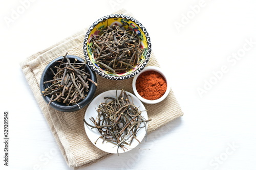 Saffron seasoning in root and powder, exhibited in containers on white wooden board