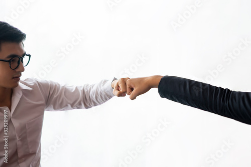 asian businessmen fist bumping each other giving respect to one another with teamwork, handsome asian man wearing a white long sleeves shirt with black smart glasses with a white isolated background photo