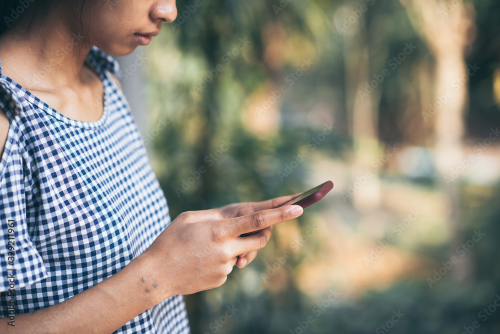 Young asian woman using mobile phone outdoor nature blurry backgrounds. Young asian woman using mobile phone outdoor nature blurry backgrounds.