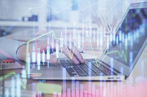 Double exposure of stock market graph with man working on laptop on background. Concept of financial analysis. © peshkova