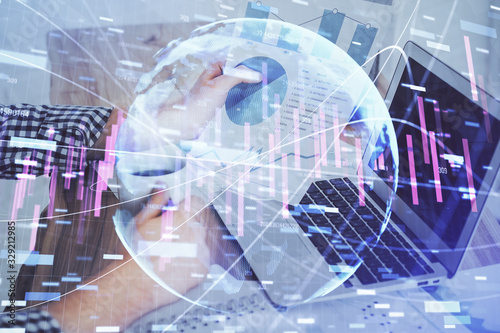 Double exposure of stock graph with businessman typing on computer in office on background. Concept of hard work.