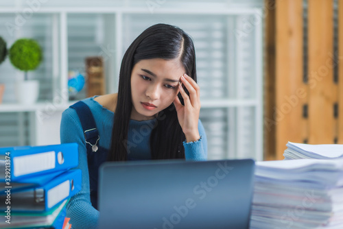 Young beautiful asian woman tried from work in the office with stack of papers.