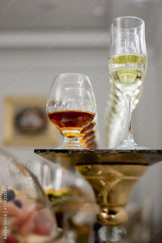 Obraz premium Close up of lot of glasses of fresh cognac and champagne on bar table. Party and holiday celebration concept