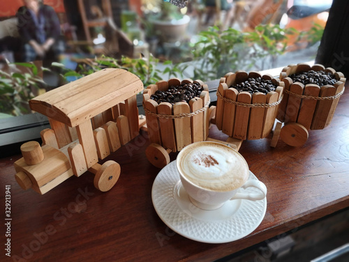 Fototapeta Naklejka Na Ścianę i Meble -  Wooden Train with coffee beans in the buckets and a cup of capucino cofee
