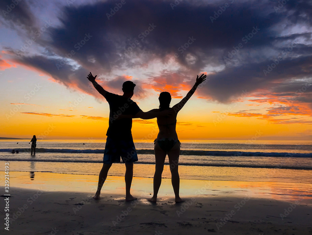 Silhouettes of couple in love at beach sunset celebrating freedom and love