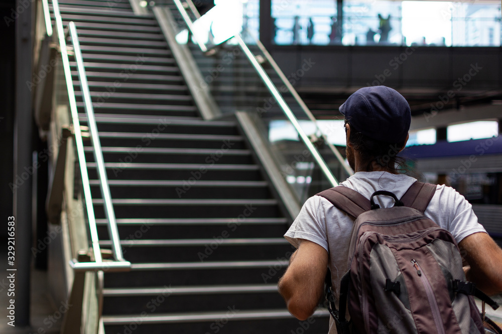 Boy with backpack and beret at the train station for climbing the stairs