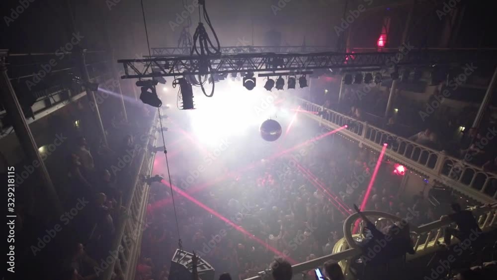 Red light rays blinking at a techno event, crowd dancing and raising hands to music, at a nightclub, in Amsterdam, Netherlands