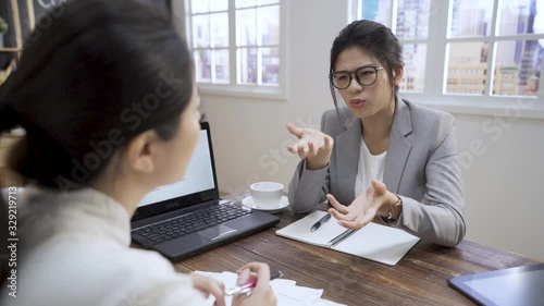 asian korean woman explaining thought. two female business people having talk negotiating. serious lady having conversation colleague discussing issues at meeting in cafe.