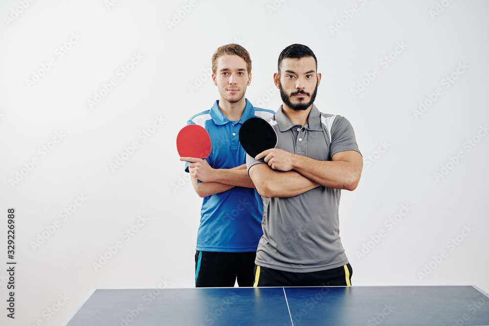 Portrait of multi-ethnic team of table tennis players in uniform posing with rackets Portrait of multi-ethnic team of table tennis players in uniform posing with rackets