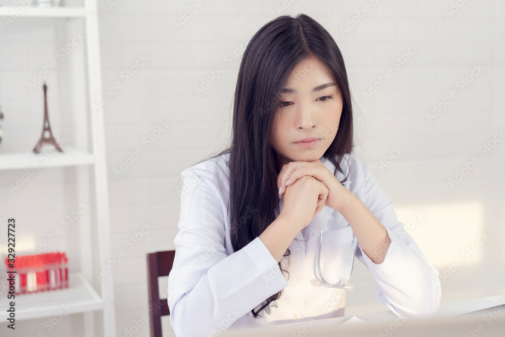 Asian female doctor is thinking about the result of an examination of her patients. Emotion with the young woman doctor being exhausted. Pensive nurse reading some information on the laptop screen Asian female doctor is thinking about the result of an examination of her patients. Emotion with the young woman doctor being exhausted. Pensive nurse reading some information on the laptop screen