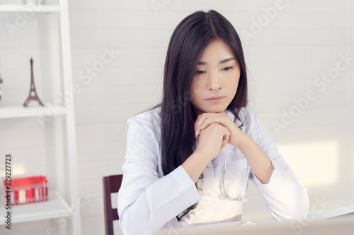 Asian female doctor is thinking about the result of an examination of her patients. Emotion with the young woman doctor being exhausted. Pensive nurse reading some information on the laptop screen