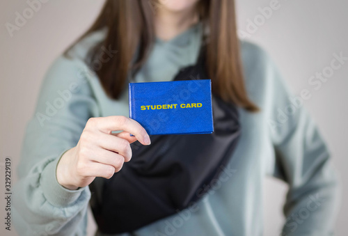 Girl holds a blue student card. Close up. Isolated on a gray background