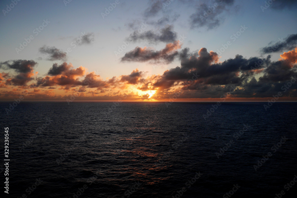 An orange sunset over a calm Caribbean Sea seen from a cruise ship