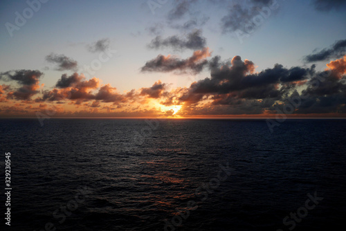 An orange sunset over a calm Caribbean Sea seen from a cruise ship