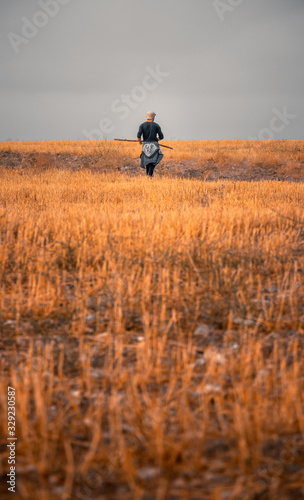 moody portrait of a solo traveller walking through colorful and endless fields alone by himself and enjoying the beautiful nature and silence and peace of it.