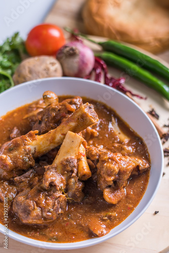 Hot and spicy Singapore's national dish the sup tulang made out of mutton bone marrow in a white bowl and white background photo