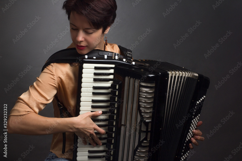 A brunette in a gold shirt, with short haircut, on a light gray background of the Studio. With accordion musician