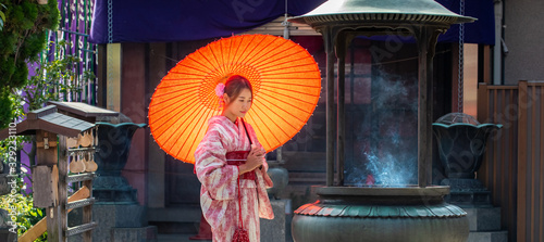Foto Portrait of Happy young beautiful Asian woman girls wearing pink traditional japanese kimono dress holding red paper umbrella parasol standing in Japanese temple shrine with smiling face