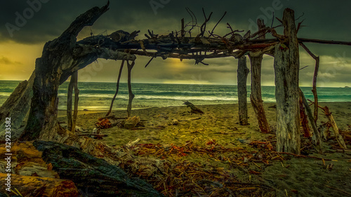Beach shelter made from driftwood on a moody dramatic stormy day © Stewart