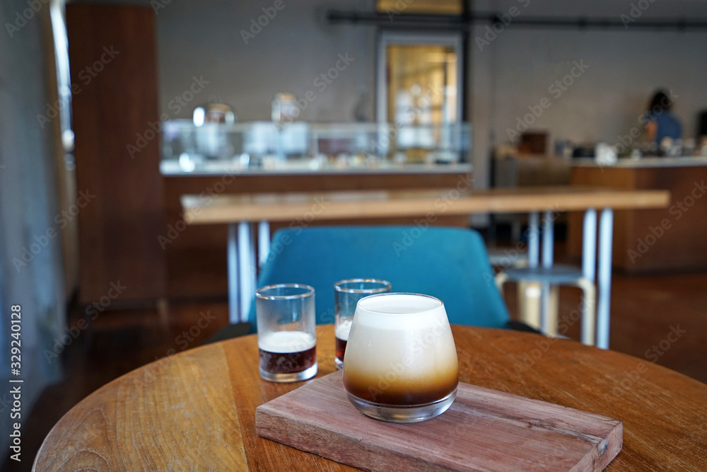 Close up glass cup of Nitro cold brew coffee on wooden tray table ,black coffee slowly infusing with nitrogen gas Close up glass cup of Nitro cold brew coffee on wooden tray table ,black coffee slowly infusing with nitrogen gas