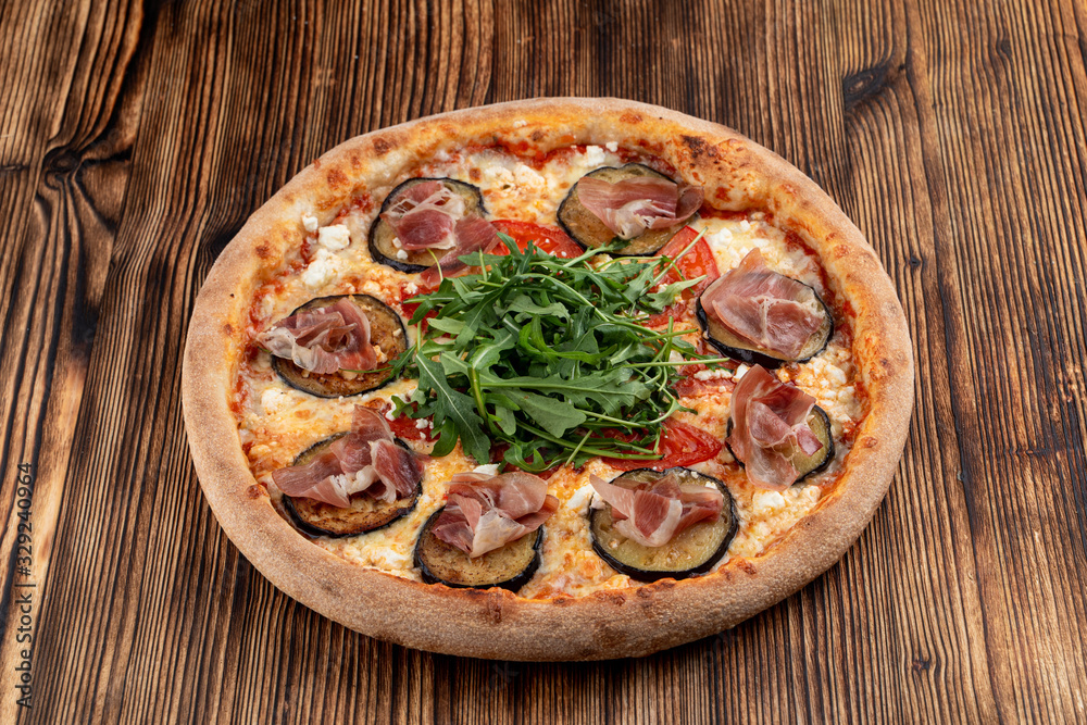 Italian pizza with grilled eggplant, arugula, tomatoes, parma ham and sirtaki cheese Italian pizza with grilled eggplant, arugula, tomatoes, parma ham and sirtaki cheese