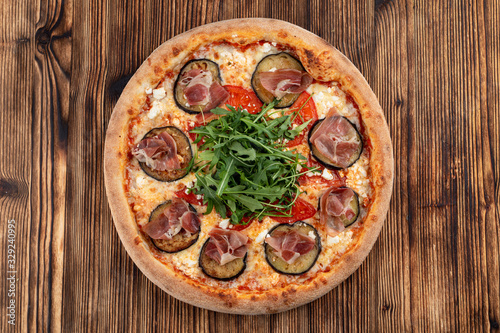 Italian pizza with grilled eggplant, arugula, tomatoes, parma ham and sirtaki cheese #329240995