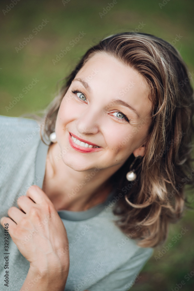 Stock photo headshot of an attractive young woman with dyed middle length hair with red lips and earrings smiling at camera with happiness. Blurred background. Stock photo headshot of an attractive young woman with dyed middle length hair with red lips and earrings smiling at camera with happiness. Blurred background.