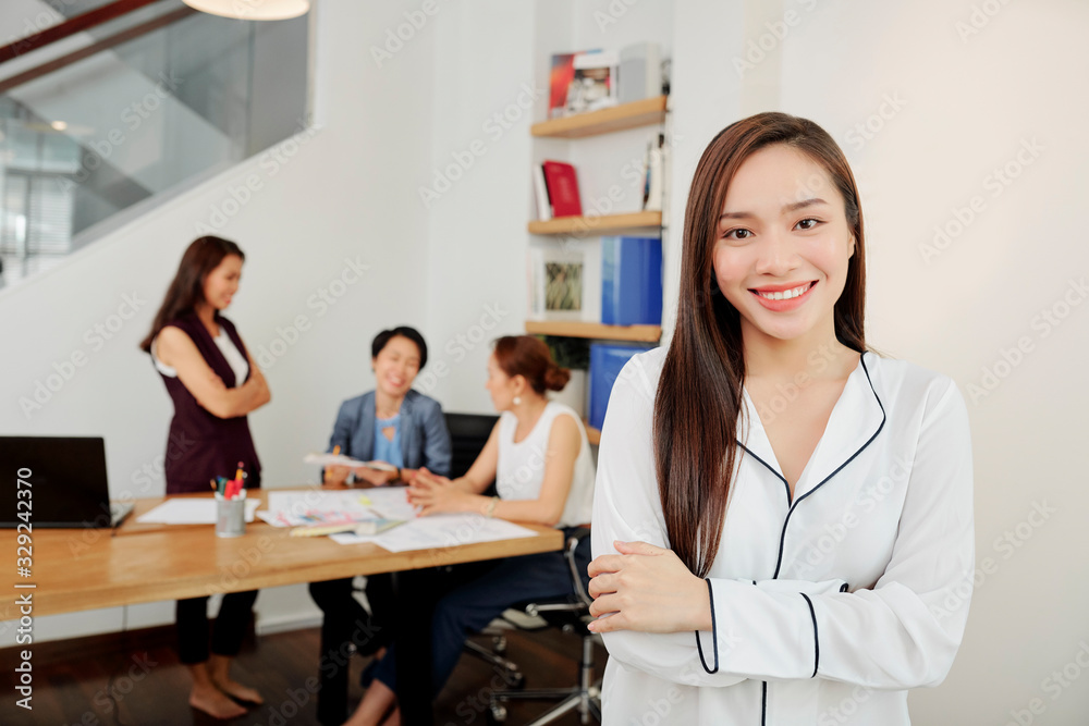 Charming young Vietnamese business lady with long hair folding arms and looking at camera Charming young Vietnamese business lady with long hair folding arms and looking at camera