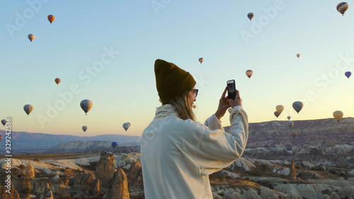 Young female taking pictures of air balloons by iphone