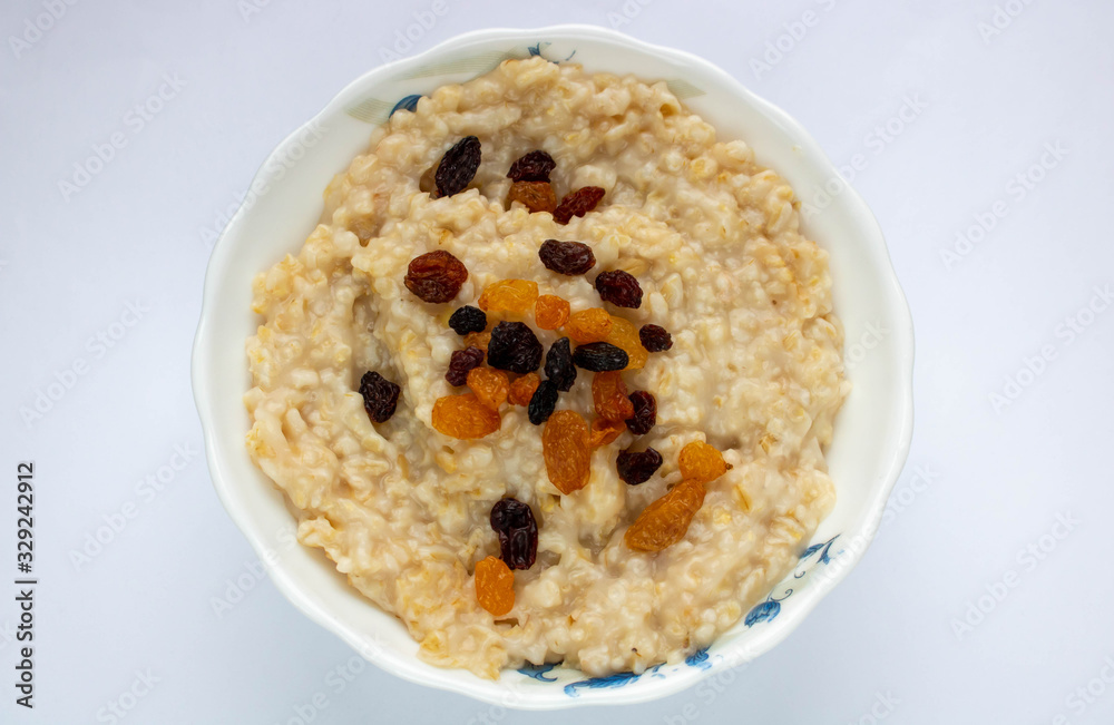 Bowl of oatmeal with raisins. Top view, isolated on white.