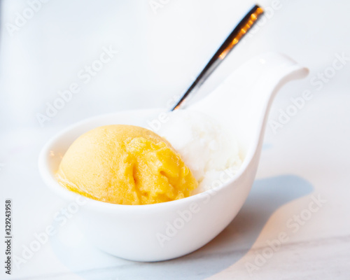 Mango and coconut ice cream served on mini white bowl