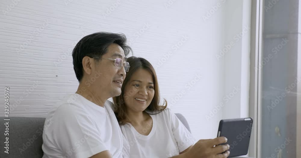 Happy senior couple using tablet computer together at living room Happy senior couple using tablet computer together at living room